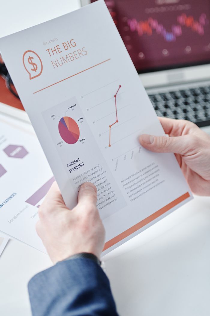 services-02 Close-up of hands holding a business report with data charts and graphs displaying financial information.