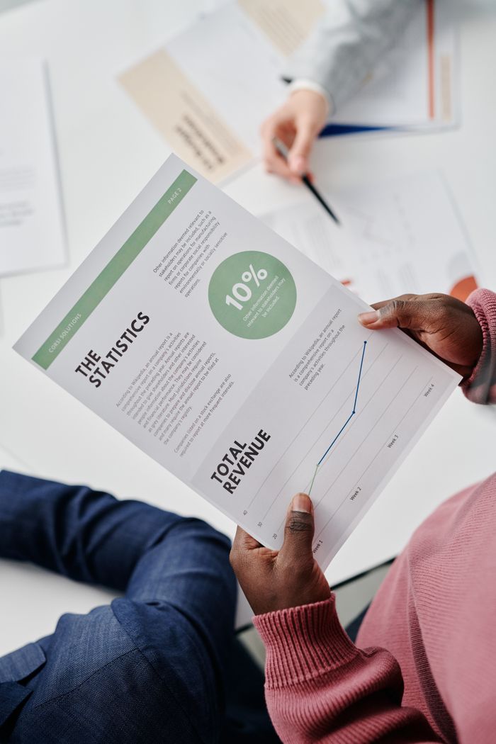 Adults reviewing statistical business reports in a professional office environment.